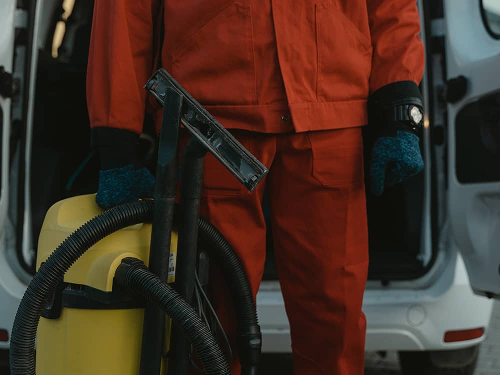 Person vor einem Van mit Staubsauger in der Hand
